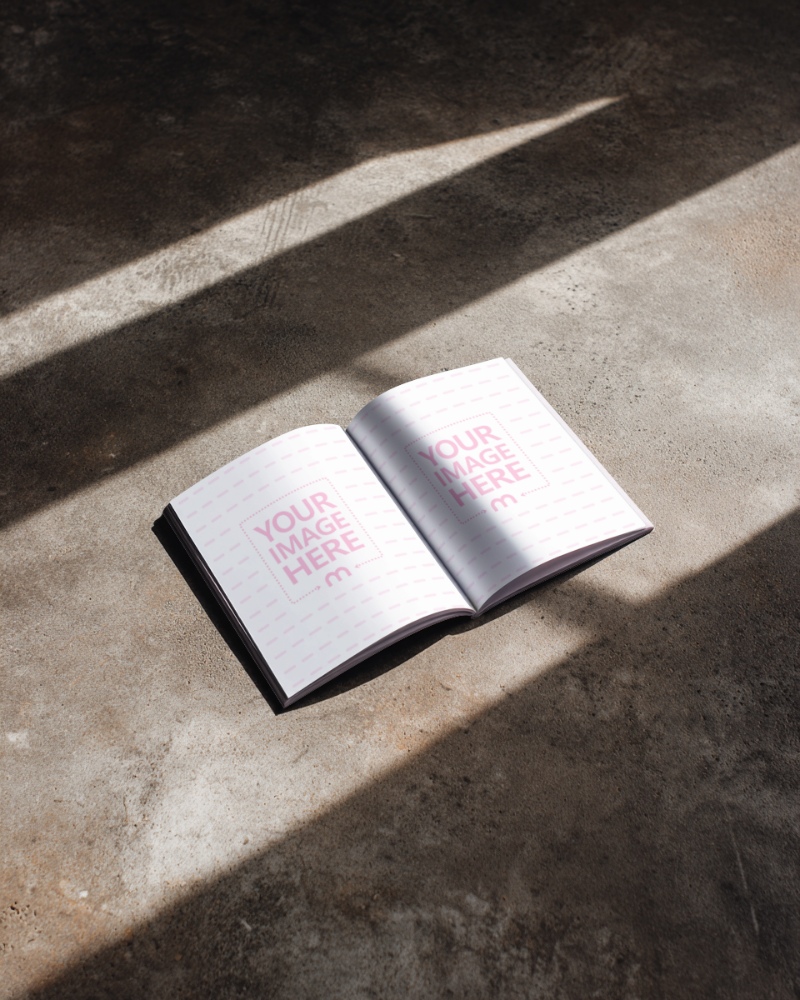 Open Book Page Mockup on Concrete Floor with Natural Light preview image