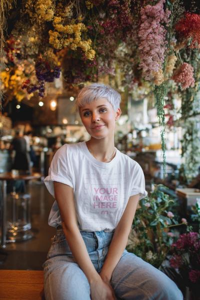 T-Shirt Mockup with Woman in Cafe-Themed Scene and Colorful Decor