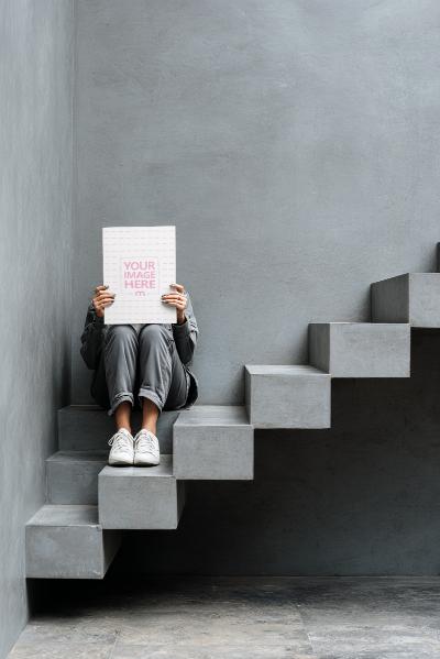 Poster Mockup Held by Seated Person in Modern Concrete Interior