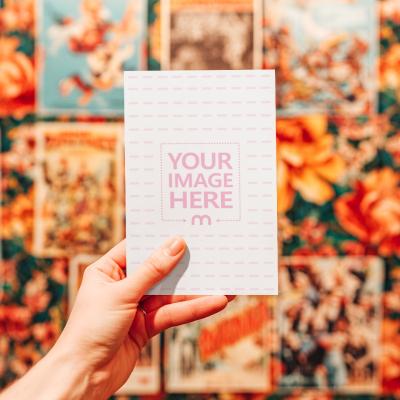 Poster Mockup Held by Hand in Front of Vintage Posters