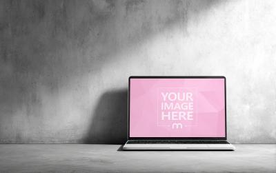 Laptop Mockup on Concrete Floor Against Wall in Industrial Scene
