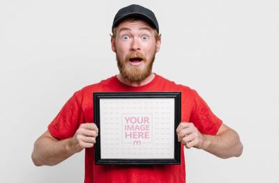 Framed Poster Mockup Held by Surprised Man for Promotional Display